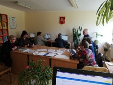 Prie stalo ir kompiuterių bibliotekoje sėdi skaitytojai, mokymus veda Janina Vyšniauskienė